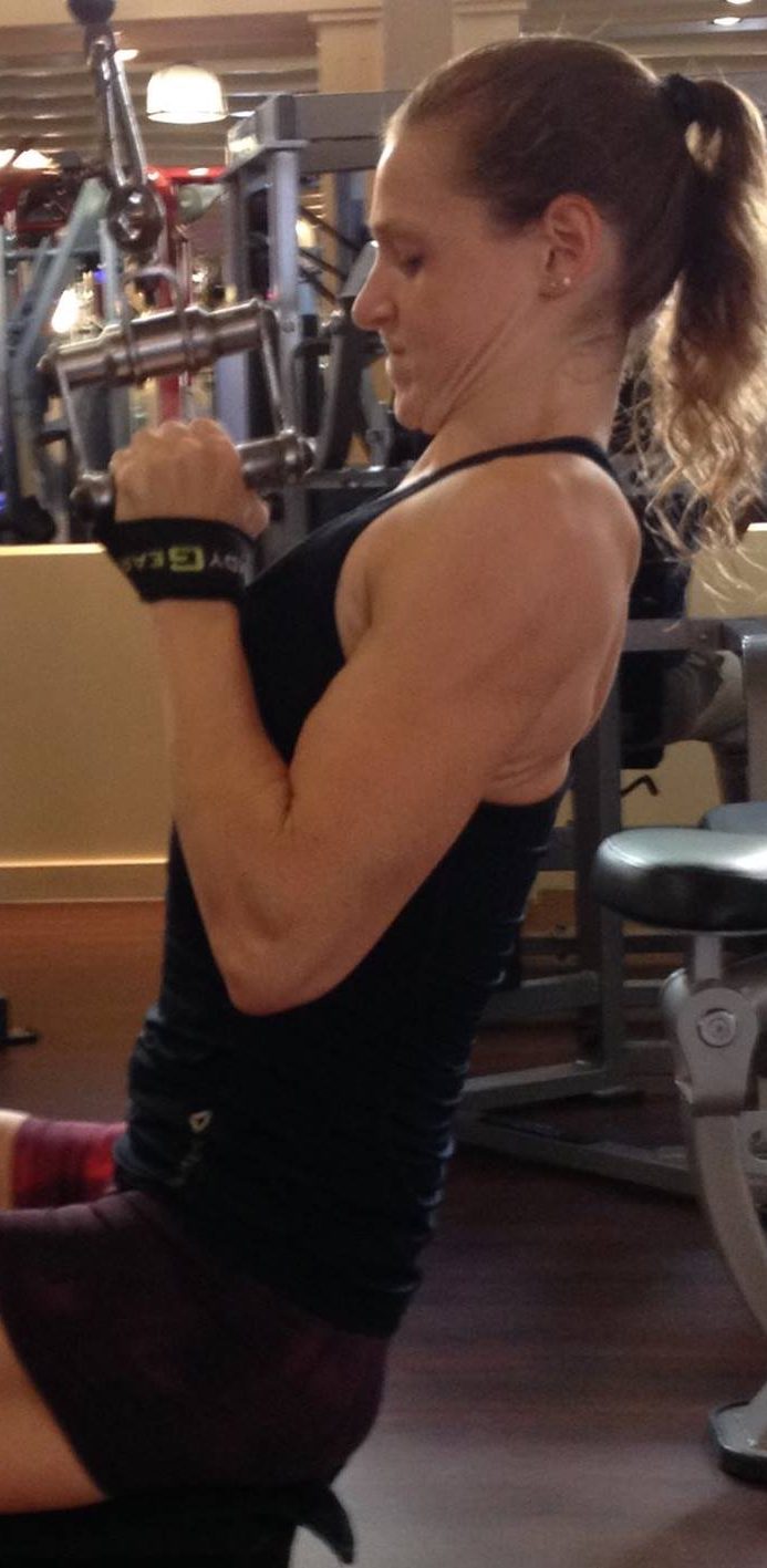 Christa doet een oefening met een fitness apparaat in een sportschool.