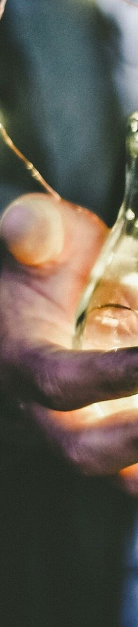 Een hand houdt een gloeilamp vol met warme, sprankelende lichtjes.