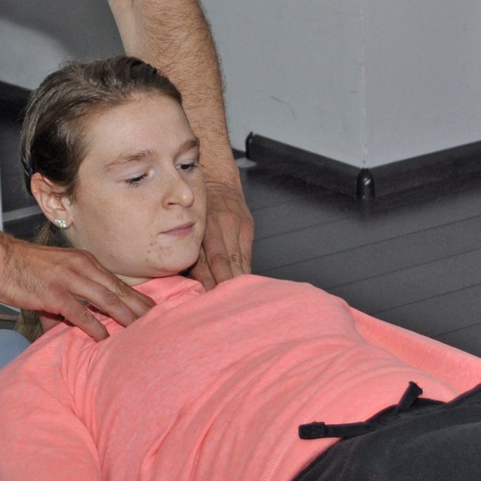 Christa doet een Pilatesoefening op een pilates apparaat in een oefenruimte.